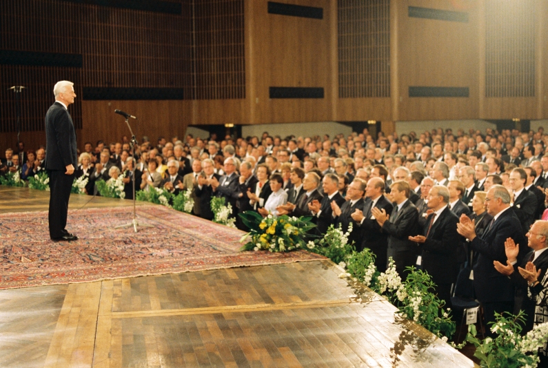 Richard von Weizsäcker auf der Bühne in der Bonner Beethovenhalle, am Mikrofon stehend und festlich gekleidet, das Plenum applaudiert