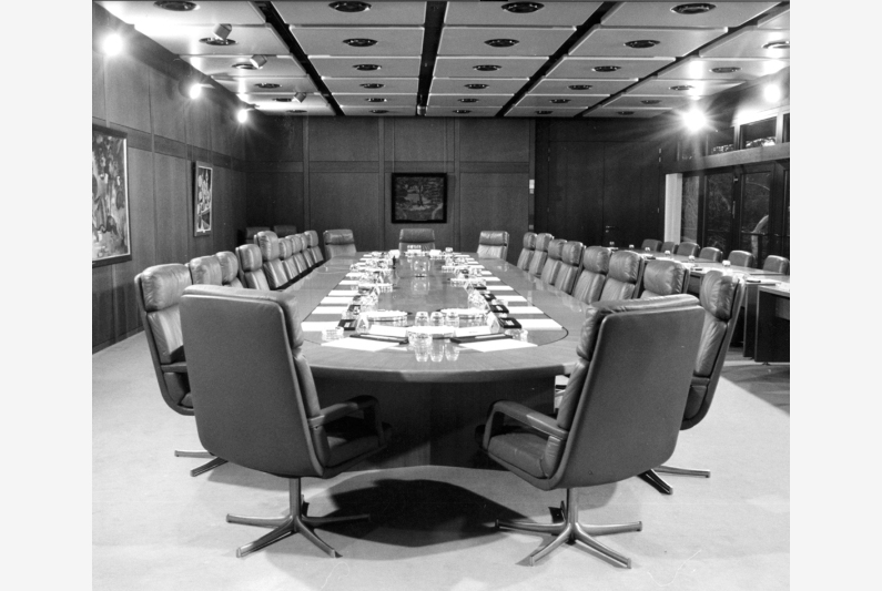 Black-and-white photography, large wood-panelled hall with long cabinet table and paintings on the walls