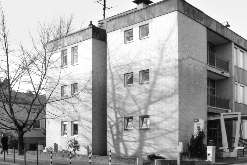 Schwarzweiß-Fotografie des ehemaligen Bonner Studios des WDR an der Dahlmannstraße, ein schlichter, dreigeschossiger Flachdachbau mit kleinen Fenstern, davor ein Baum