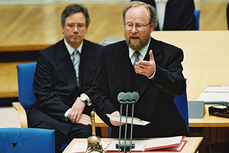 Wolfgang Thierse standing at the lectern of the plenary hall of the Bundestag in Bonn, in front of him a microphone.