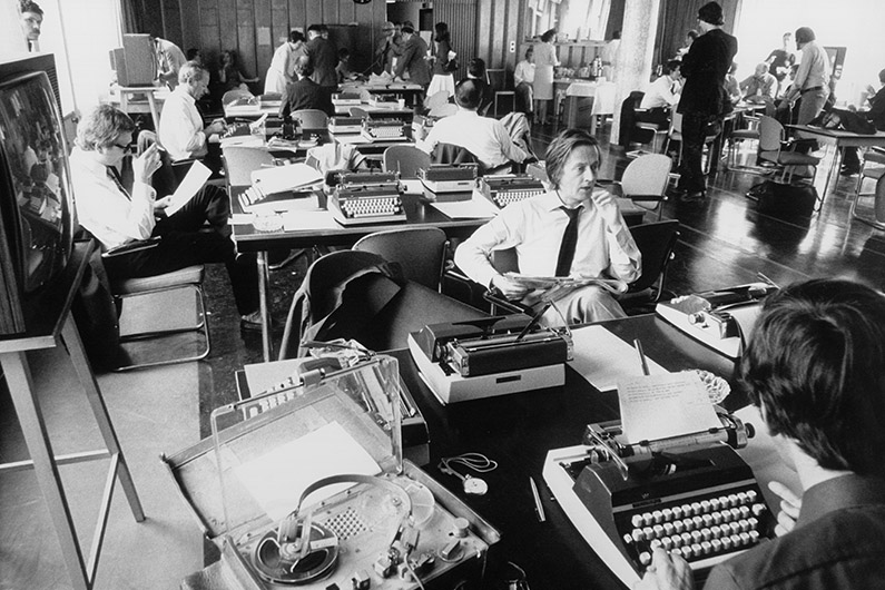 Black and white photography, journalists in an office, sitting at desks with typewriters.